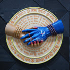 Decorative plate with hands and text on a textured surface